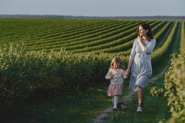 Madre embarazada con su hija en un campo