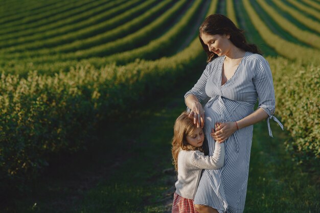 Madre embarazada con su hija en un campo