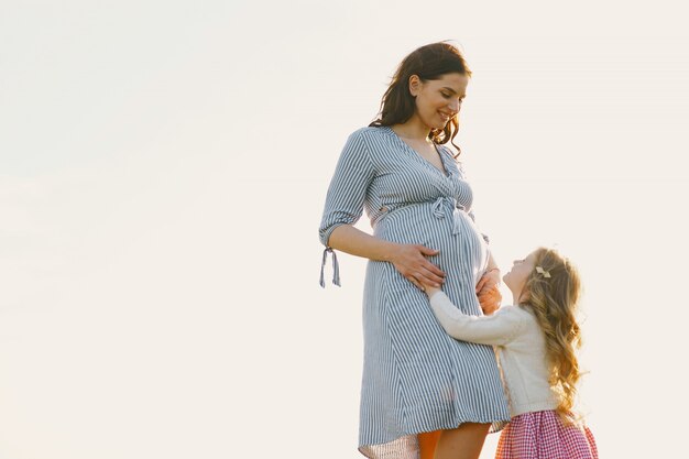 Madre embarazada con su hija en un campo