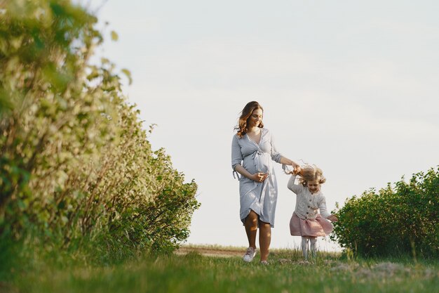 Madre embarazada con su hija en un campo