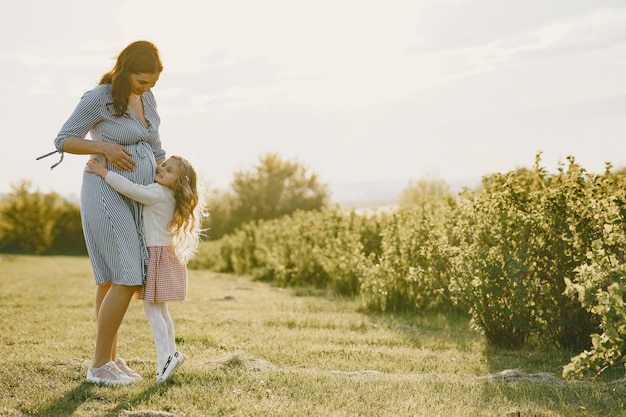 Madre embarazada con su hija en un campo