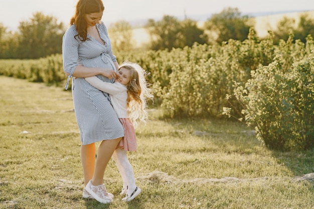 Madre embarazada con su hija en un campo