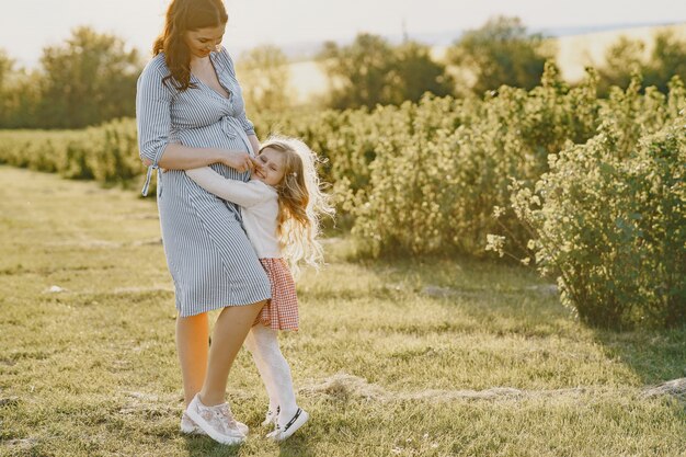 Madre embarazada con su hija en un campo