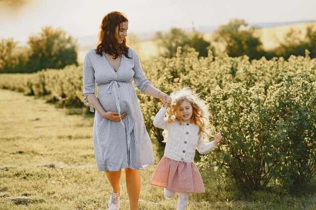 Madre embarazada con su hija en un campo