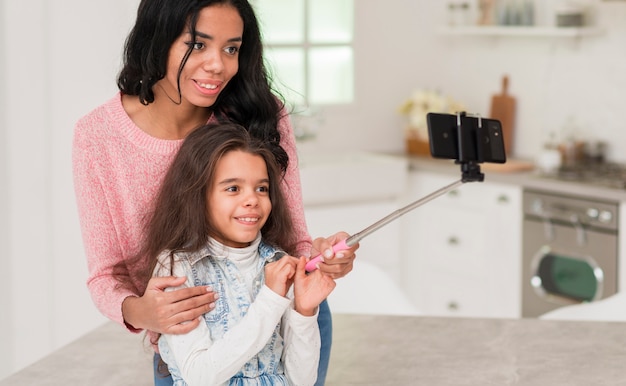 Madre enseñando a hija a tomar selfie