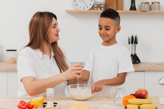 Madre enseñando a hijo a preparar comida en la cocina