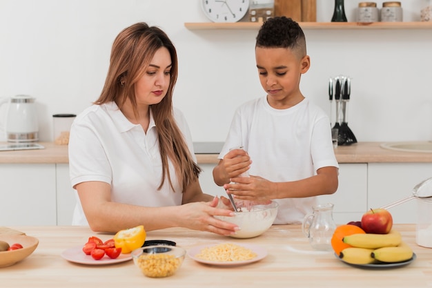 Madre enseñando a hijo a preparar comida