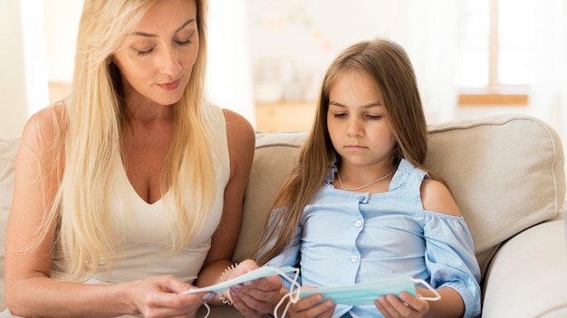 Madre enseñando a su hija sobre máscaras médicas