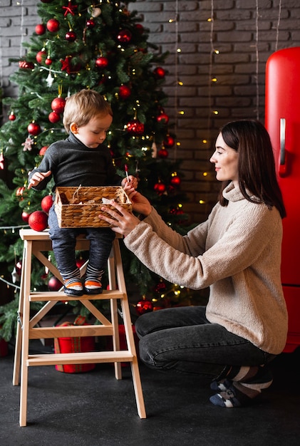 Madre enseñando a su hijo a decorar el árbol de navidad