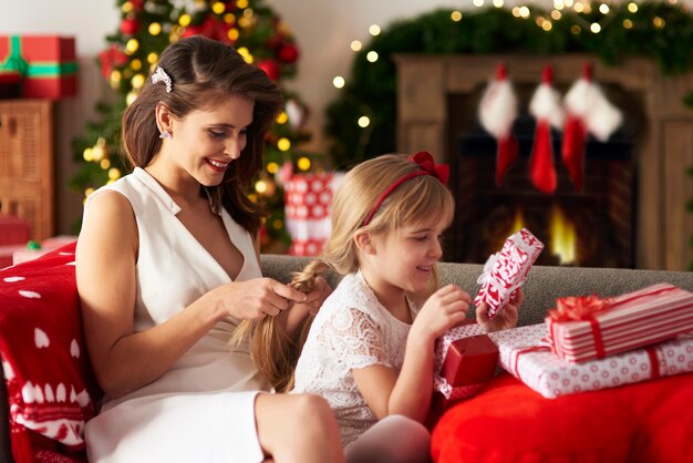 La madre está trenzando el cabello de sus hijas