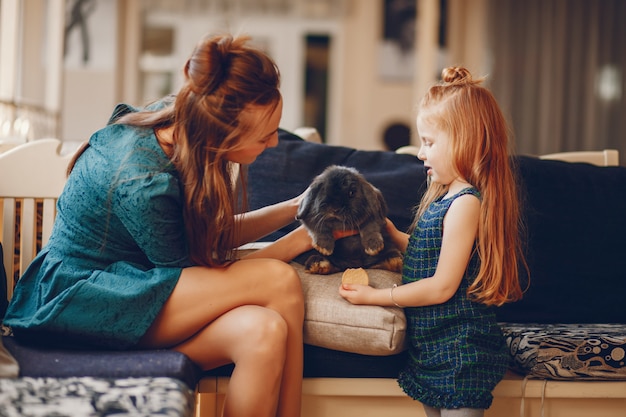 madre con estilo con cabello largo y un vestido verde jugando con su pequeña hija linda