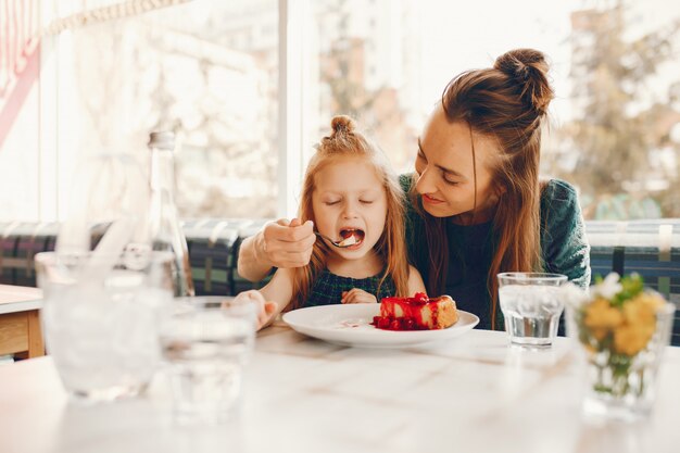 madre con estilo con cabello largo y un vestido verde sentado con su pequeña hija linda