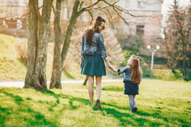 madre con estilo con el pelo largo y una chaqueta de jeans jugando con su pequeña hija linda