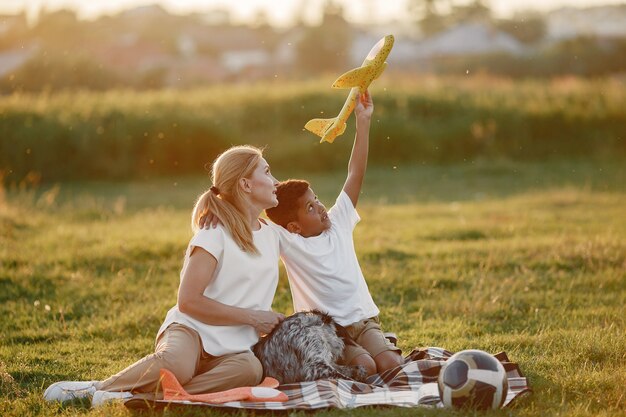 Madre europea e hijo africano. Familia en un parque de verano. Gente sentada en la manta.