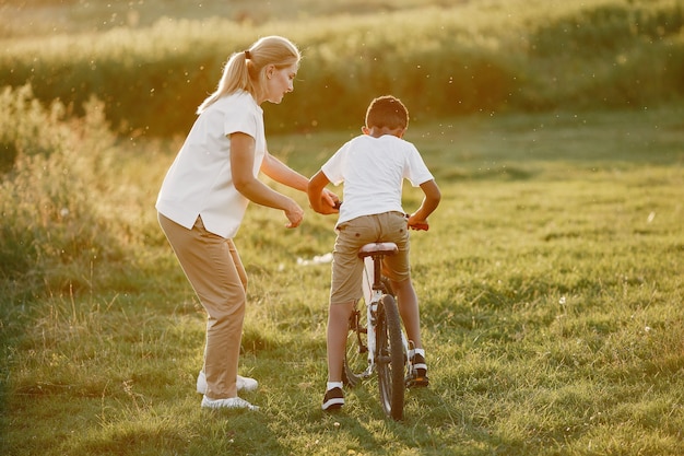 Foto gratuita madre europea e hijo africano. familia en un parque de verano. niño con bicicleta.