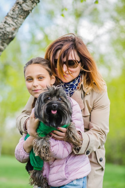 Madre feliz abrazando a su hija y al perro