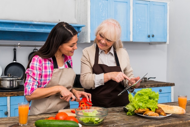 Madre feliz ayudando a su joven hija a preparar comida en la cocina