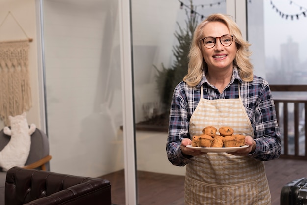 Foto gratuita madre feliz con delantal con plato de magdalenas