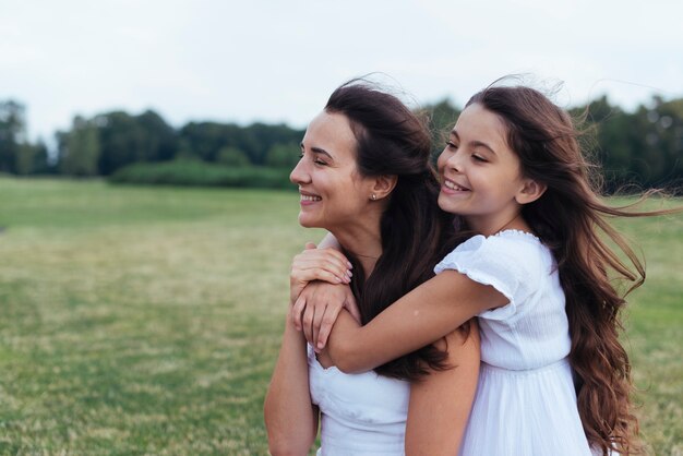 Madre feliz e hija abrazando al aire libre