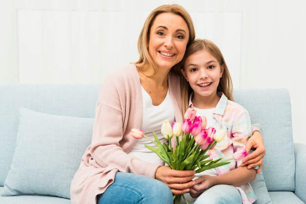 Madre feliz e hija abrazando con tulipanes