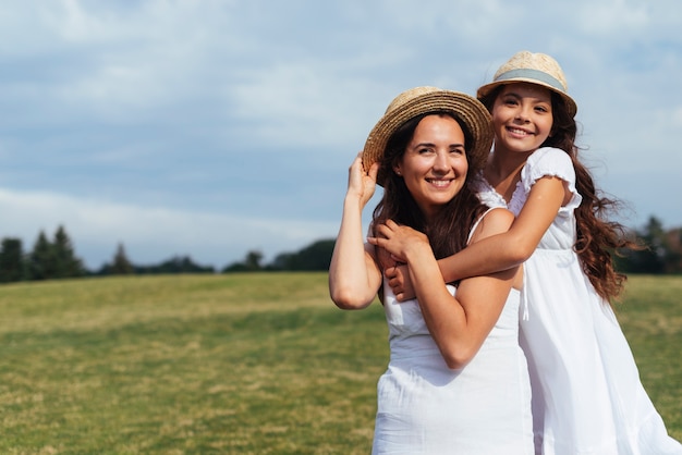 Madre feliz e hija posando en la naturaleza