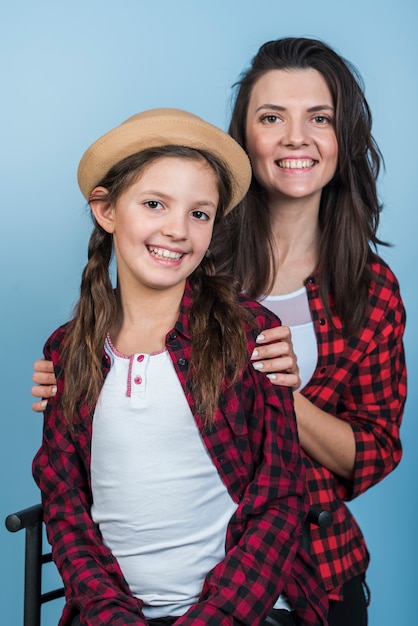 Foto gratuita madre feliz que abraza a la hija y que mira la cámara