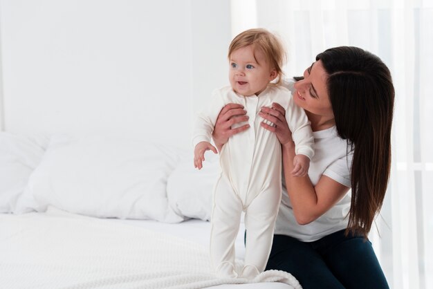 Madre feliz que celebra al bebé en cama