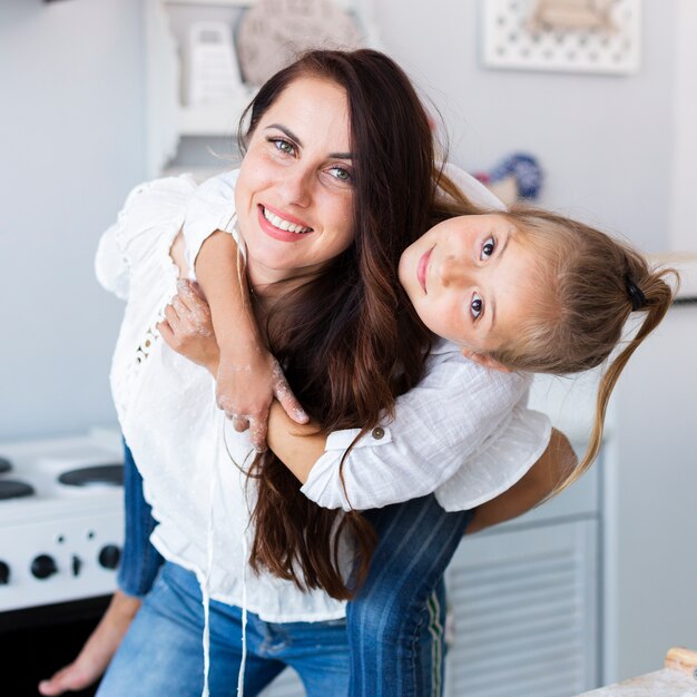 Madre feliz que detiene a su niña adorable