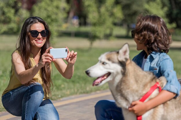 Madre fotografiando hijo con perro en el parque