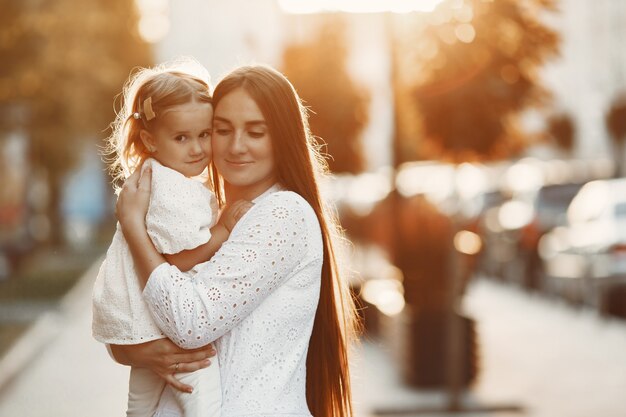 Madre con gaughter jugando. Mujer con un vestido blanco. Familia sobre un fondo de puesta de sol.