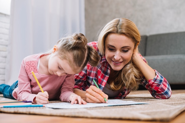 Foto gratuita madre hermosa e hija que dibujan junto en el libro en casa