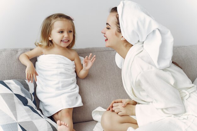 Madre con hija en bata de baño y toallas