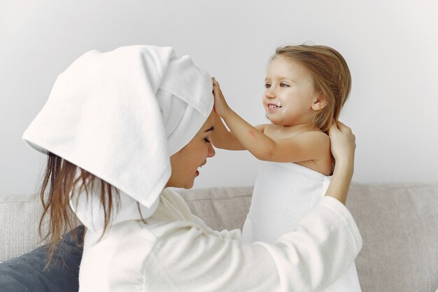 Madre con hija en bata de baño y toallas