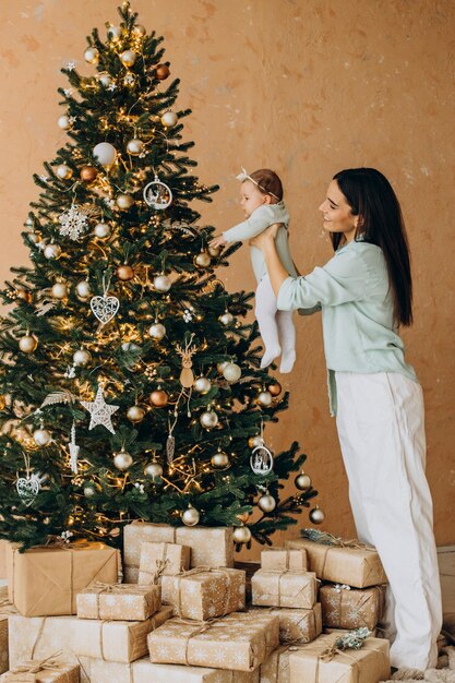 Madre, con, hija bebé, dacorating, árbol de navidad