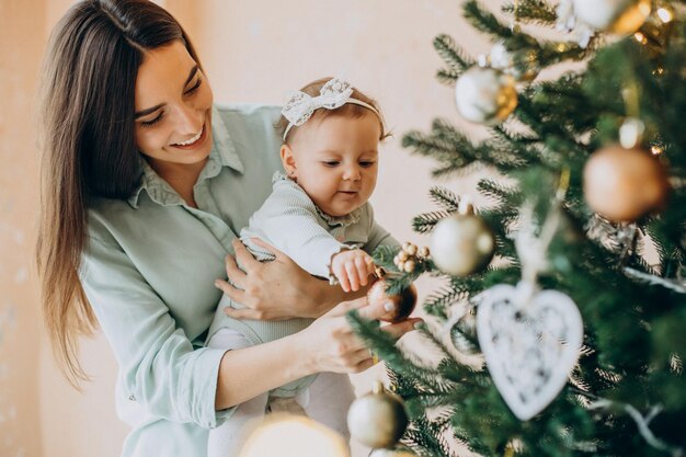 Madre, con, hija bebé, dacorating, árbol de navidad