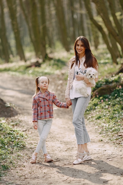 Madre con hija en un bosque de primavera con perro