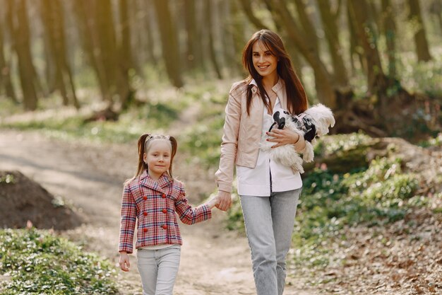 Madre con hija en un bosque de primavera con perro