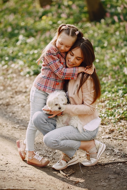 Madre con hija en un bosque de primavera con perro