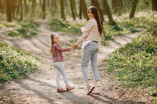 Madre con hija en un bosque de primavera con perro