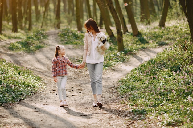 Madre con hija en un bosque de primavera con perro