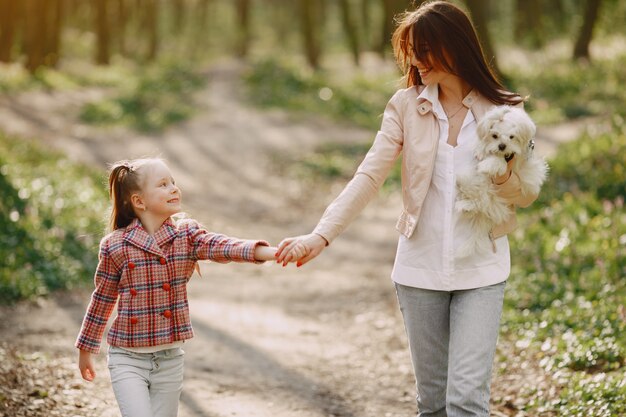 Madre con hija en un bosque de primavera con perro