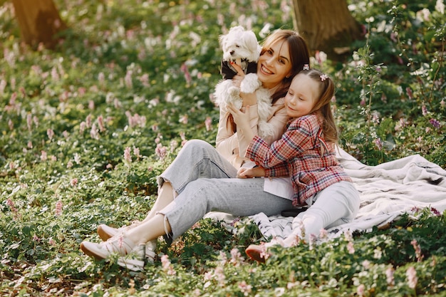 Madre con hija en un bosque de primavera con perro