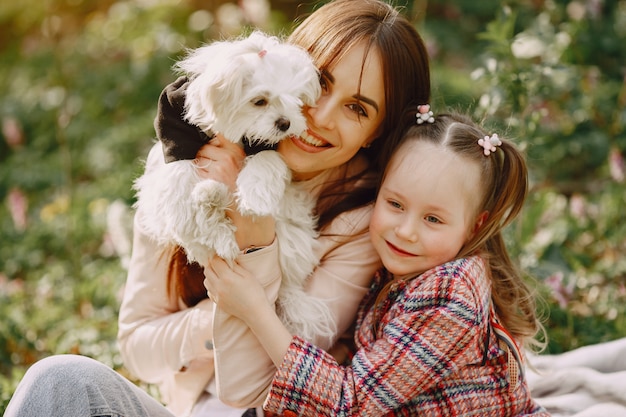 Madre con hija en un bosque de primavera con perro