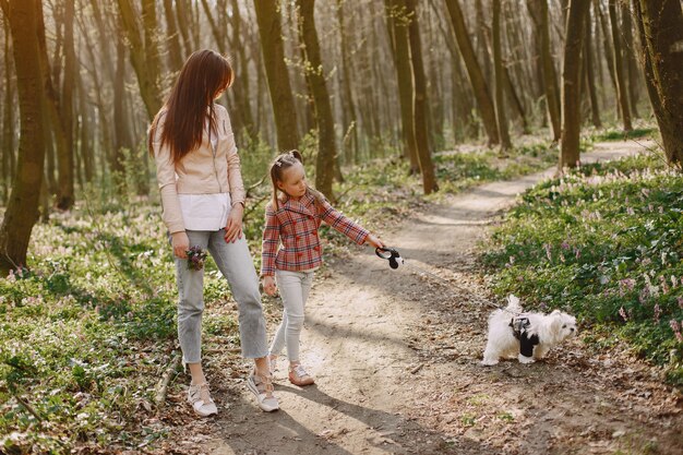 Madre con hija en un bosque de primavera con perro