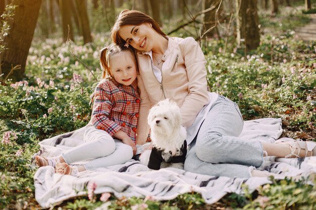 Madre con hija en un bosque de primavera con perro