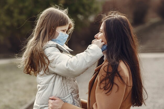 Madre con hija camina afuera en máscaras