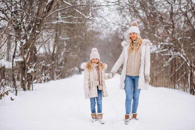 Madre con hija caminando juntos en un parque de invierno