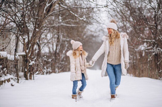 Madre con hija caminando juntos en un parque de invierno