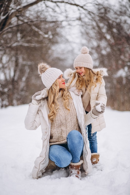 Madre con hija caminando juntos en un parque de invierno