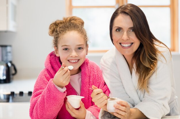 La madre y la hija de comer helado en la cocina